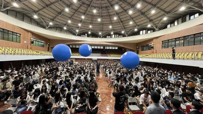 屏大新生領航營下午場在屏商校區活動中心，寫有NPTU四個字的藍色大球被新生由前往後推圖片